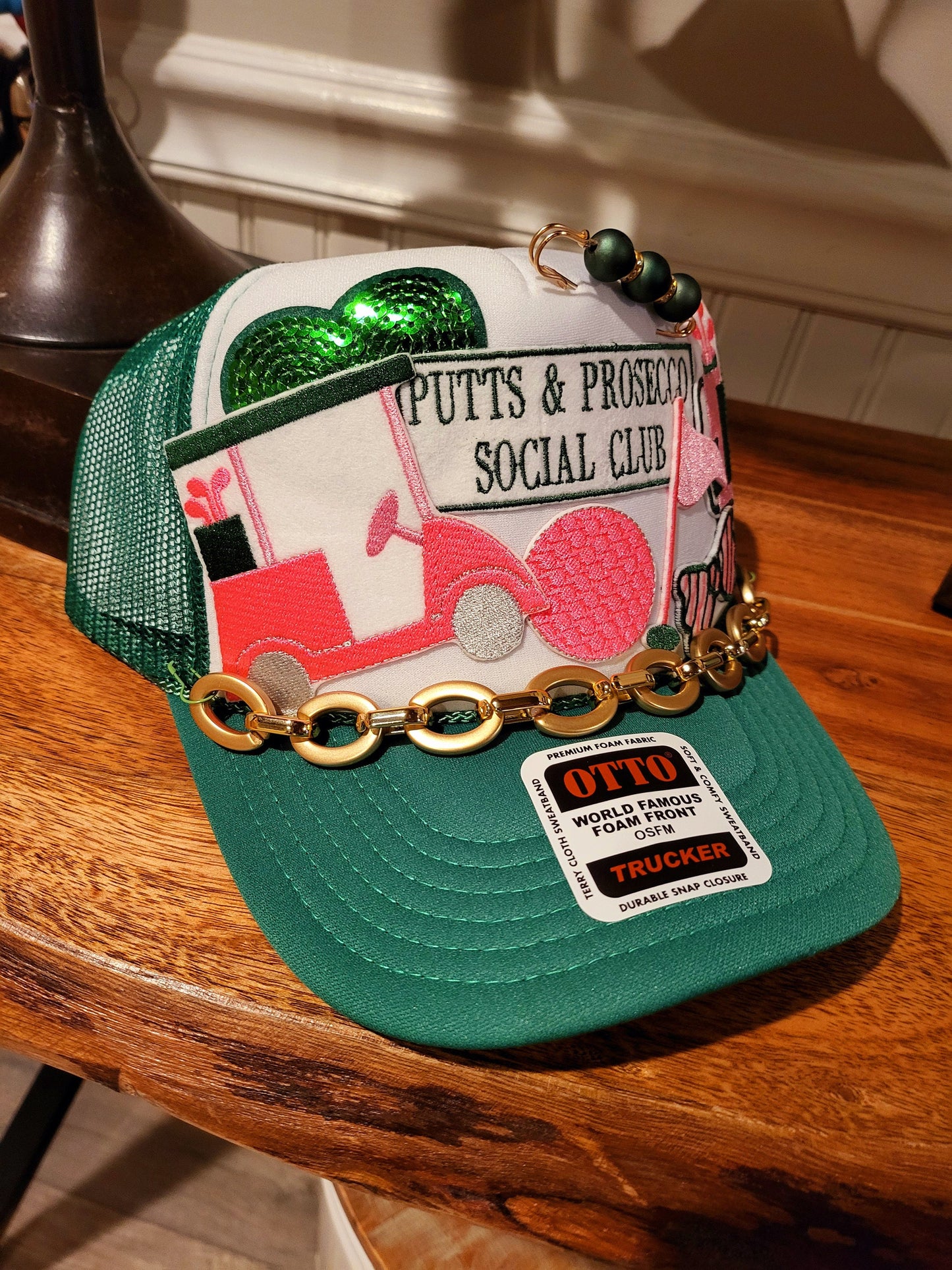 Putts and Prosecco Social Club Trucker hat with golf themed patches in pink and green.