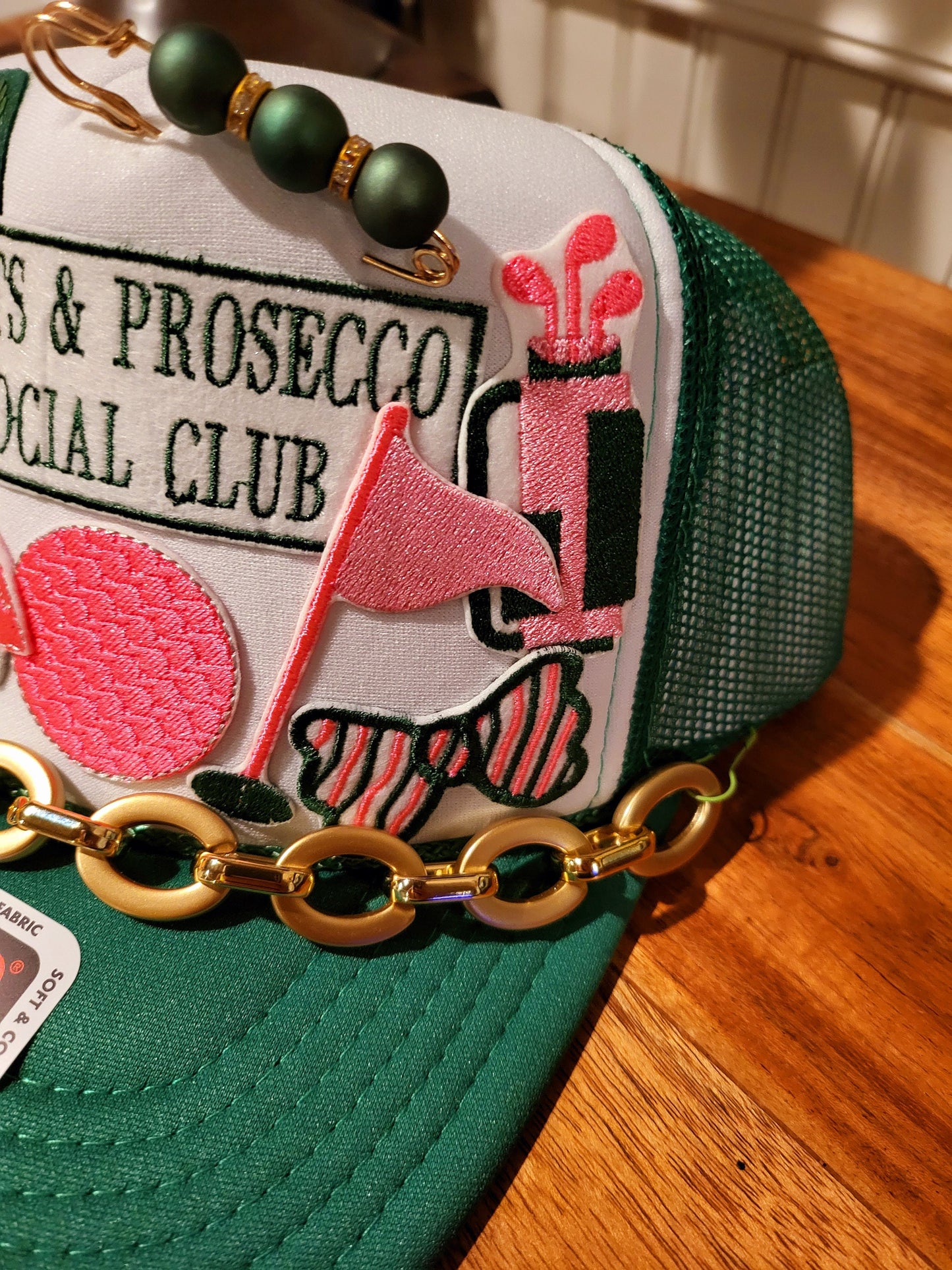Putts and Prosecco Social Club Trucker hat with golf themed patches in pink and green.